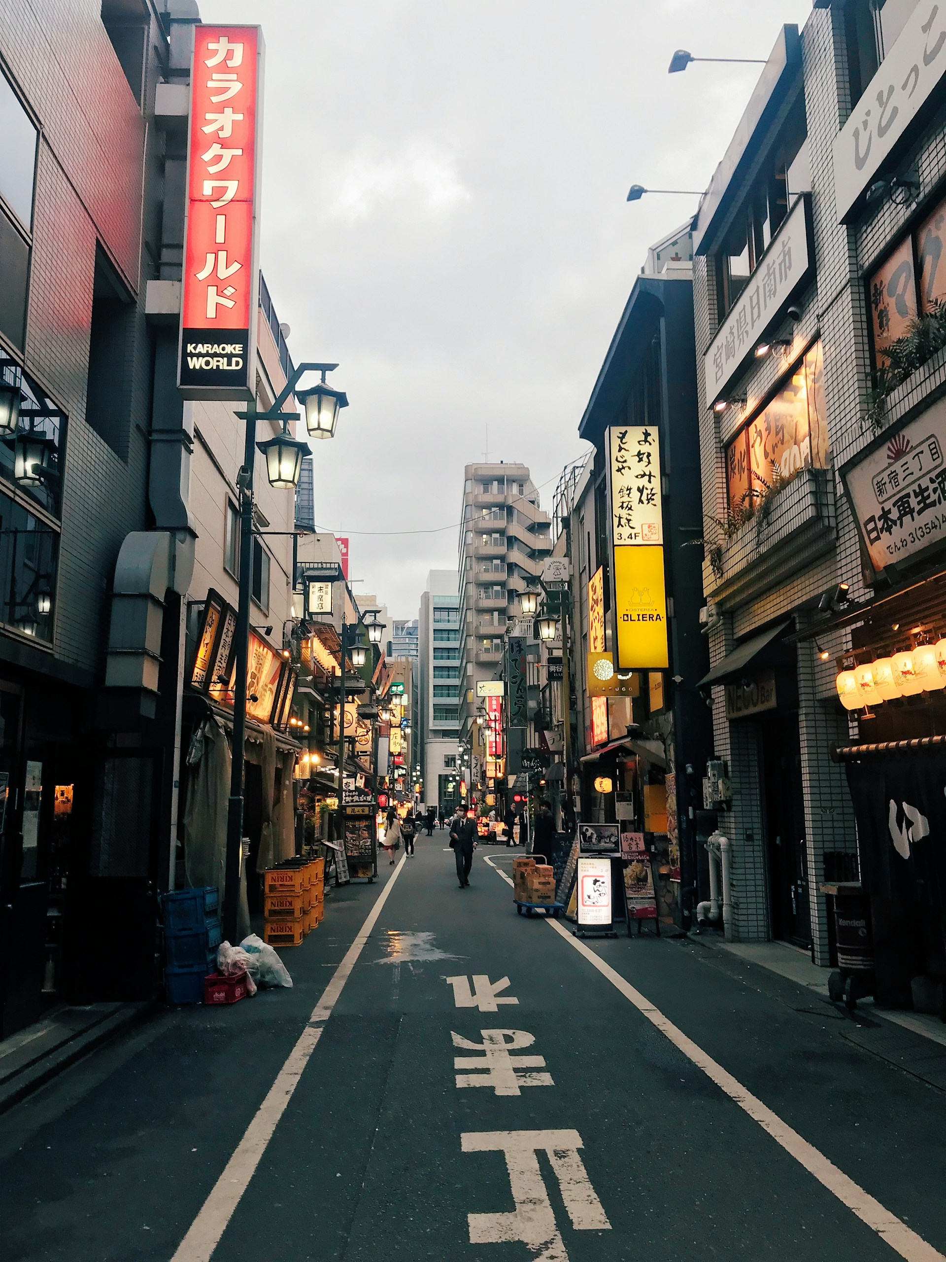 A narrow Tokyo street lined with signs, lanterns, and local businesses